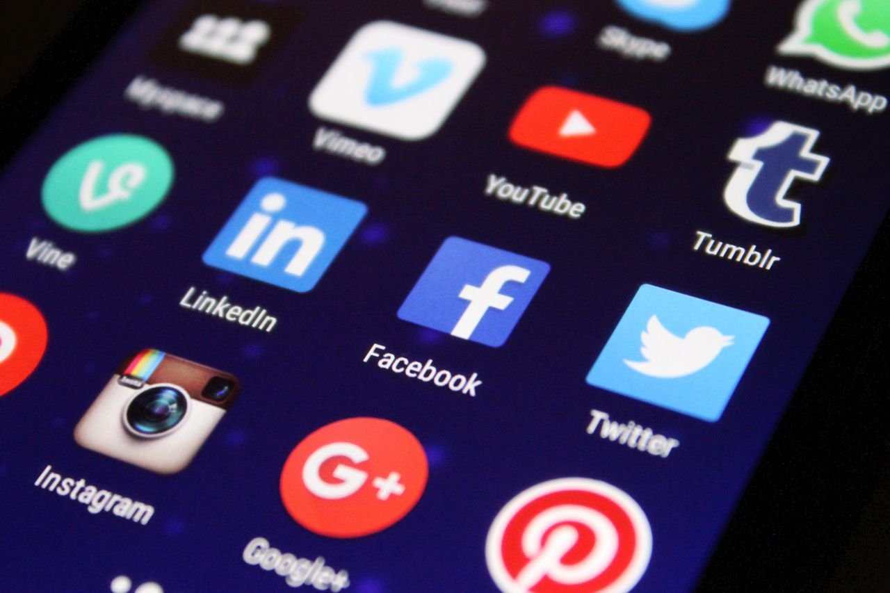 Smartphone held in hand with social media share and like icons floating above the screen