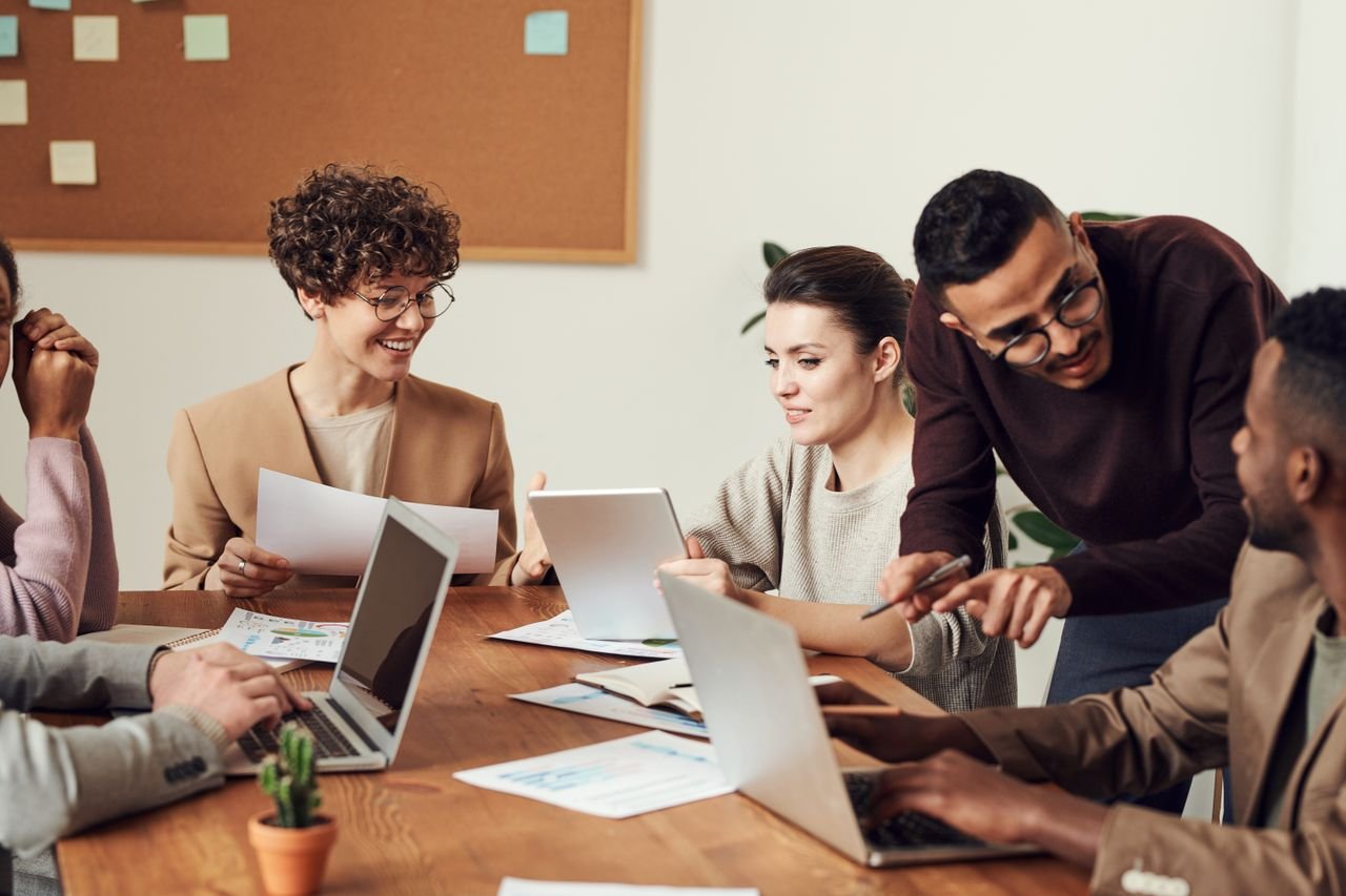 A WordPress development agency team collaborating around a table with laptops