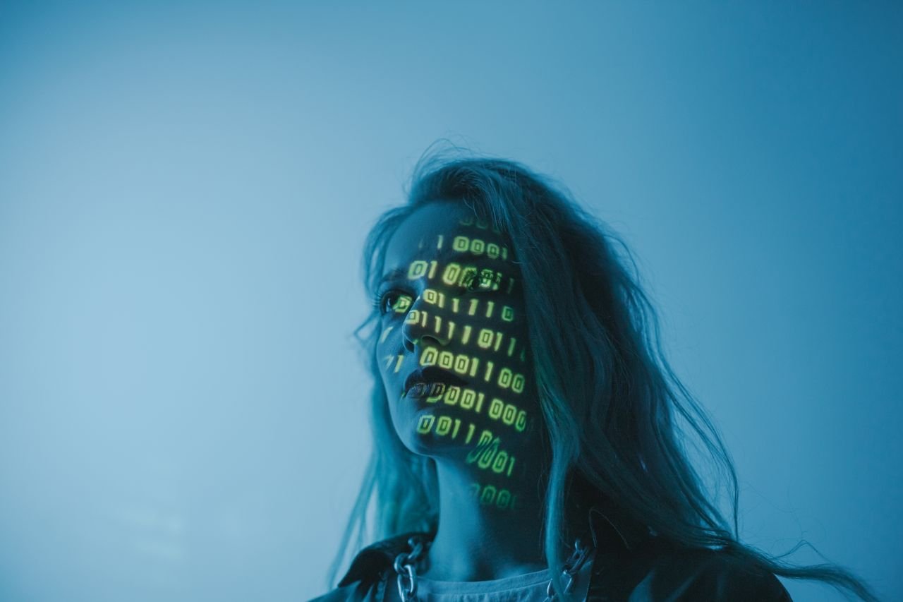 Woman lit by projected binary code against a blue background