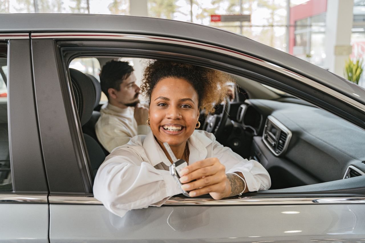 A driver sitting in a car holding the key after booking a rental